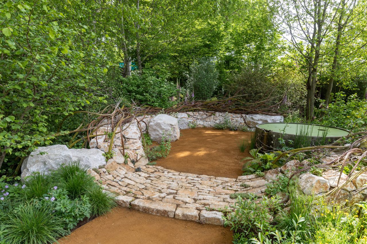 Images of the CPRE Show Garden On the Edge by Sarah Eberle. it focuses on grasses and flowers that grow around britain's edges, and is centred around a giant wooden carving of Gaia