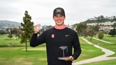 Michael Thorbjornsen holds up his ceremonial PGA Tour and the PGA Tour U trophy while smiling