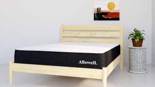 The Allswell Cool Mattress placed on a light wooden bed frame in a light gray bedroom