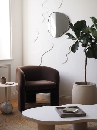 A chocolate brown velvet armchair next to a large plant