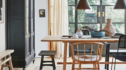 a grey sofa sit in a living room with a wooden sideboard and light grey curtains