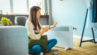 woman sat in front of large space heater in living room