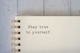 A close up of a notebook with the words 'Stay true to yourself.' typed.