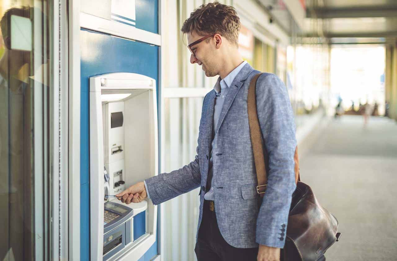 Young man is withdrawing cash from an atm machine