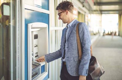 Young man is withdrawing cash from an atm machine