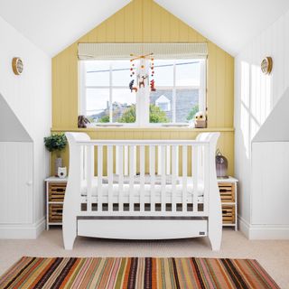 White cot, yellow wall and stripey rug