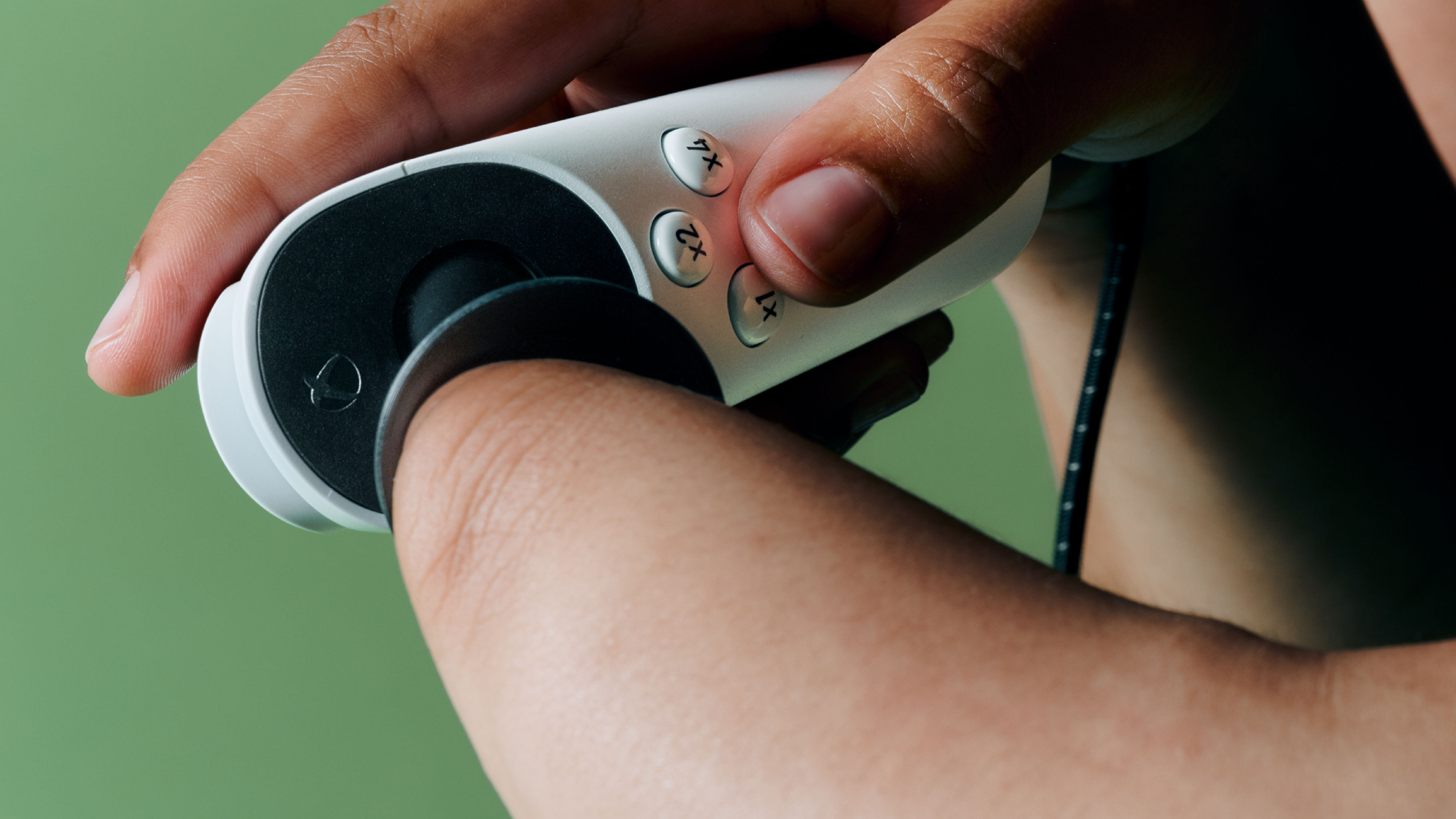 The Xbox Adaptive Joystick with a concave grip being used by a player who is using their wrist to control the stick, and a second hand for face button inputs.