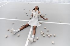 Best of tennis fashion: woman sits on tennis court surrounded by tennis balls wearing tennis whites by Brunello Cucinelli