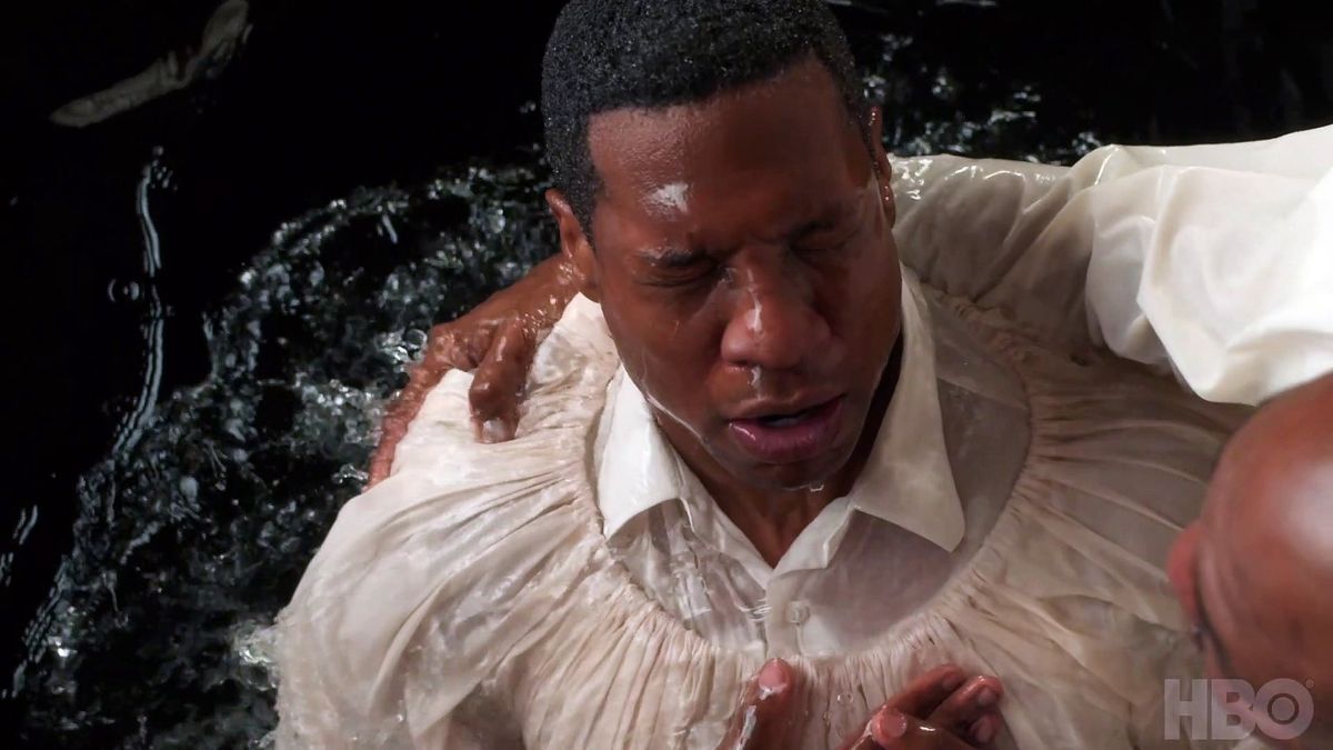 Atticus (Jonathan Majors) is baptized.