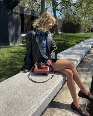 Elsa Hosk wearing a leather jacket, denim shirt, and loafers.