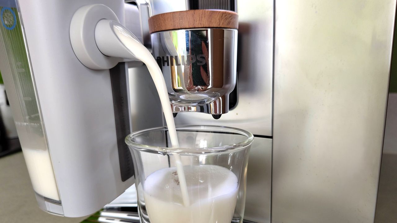 Philips Cafe Aromis Series 8000 coffee maker dispensing foamed milk into glass cup
