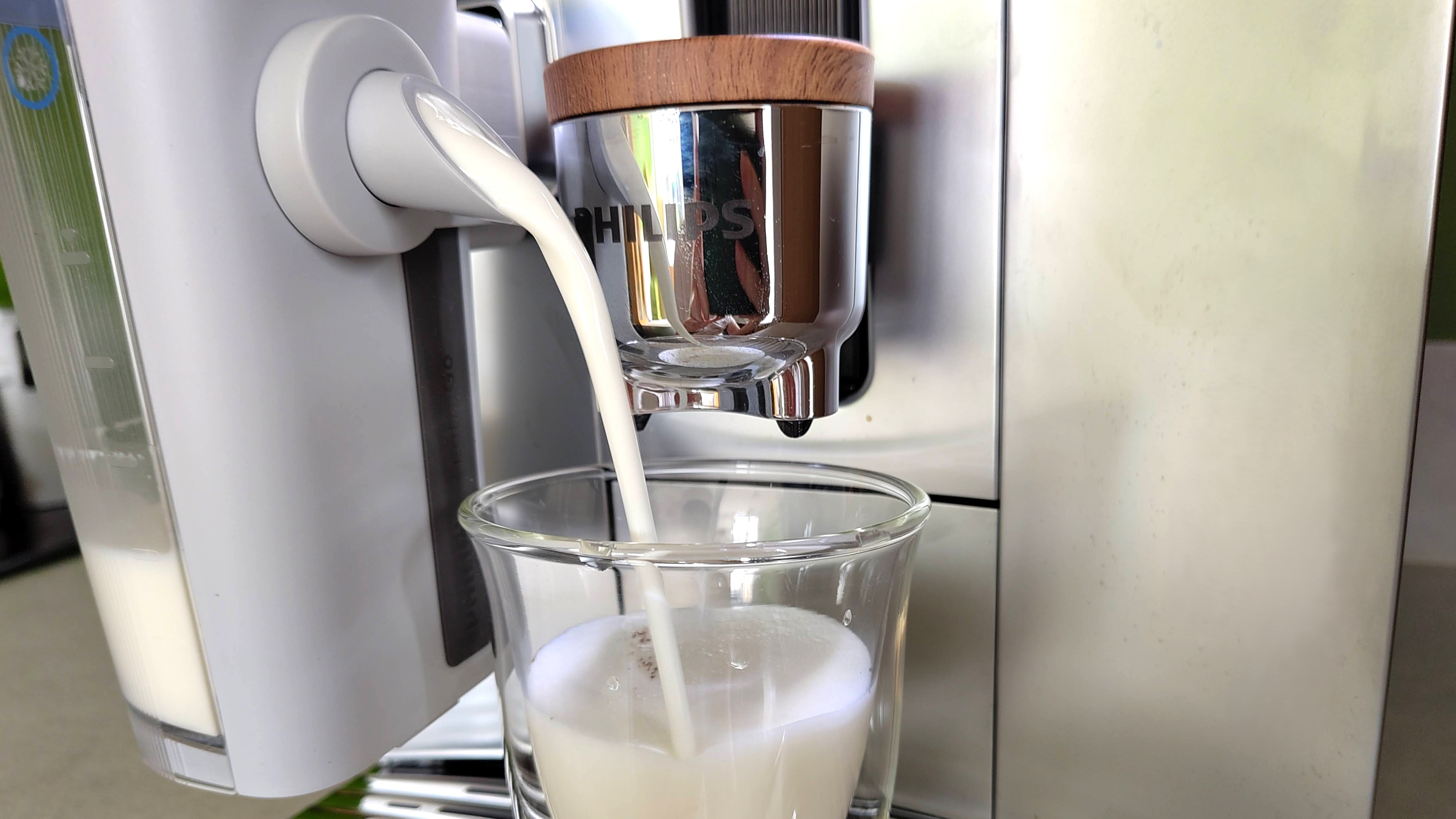 Philips Cafe Aromis Series 8000 coffee maker dispensing foamed milk into glass cup