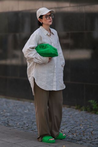 Woman in oversized linen shirt and trousers with green accessories GettyImages-1411410288