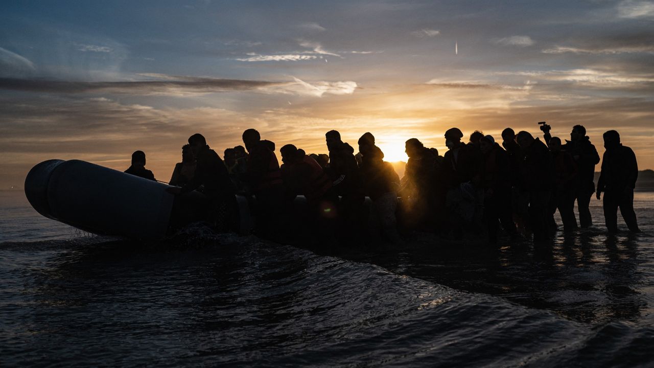 People wait to board a smuggler&#039;s inflatable dinghy in an attempt to cross the English Channel, at Bleriot beach in Sangatte, near Calais