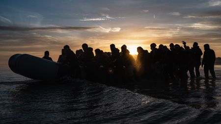 People wait to board a smuggler's inflatable dinghy in an attempt to cross the English Channel, at Bleriot beach in Sangatte, near Calais