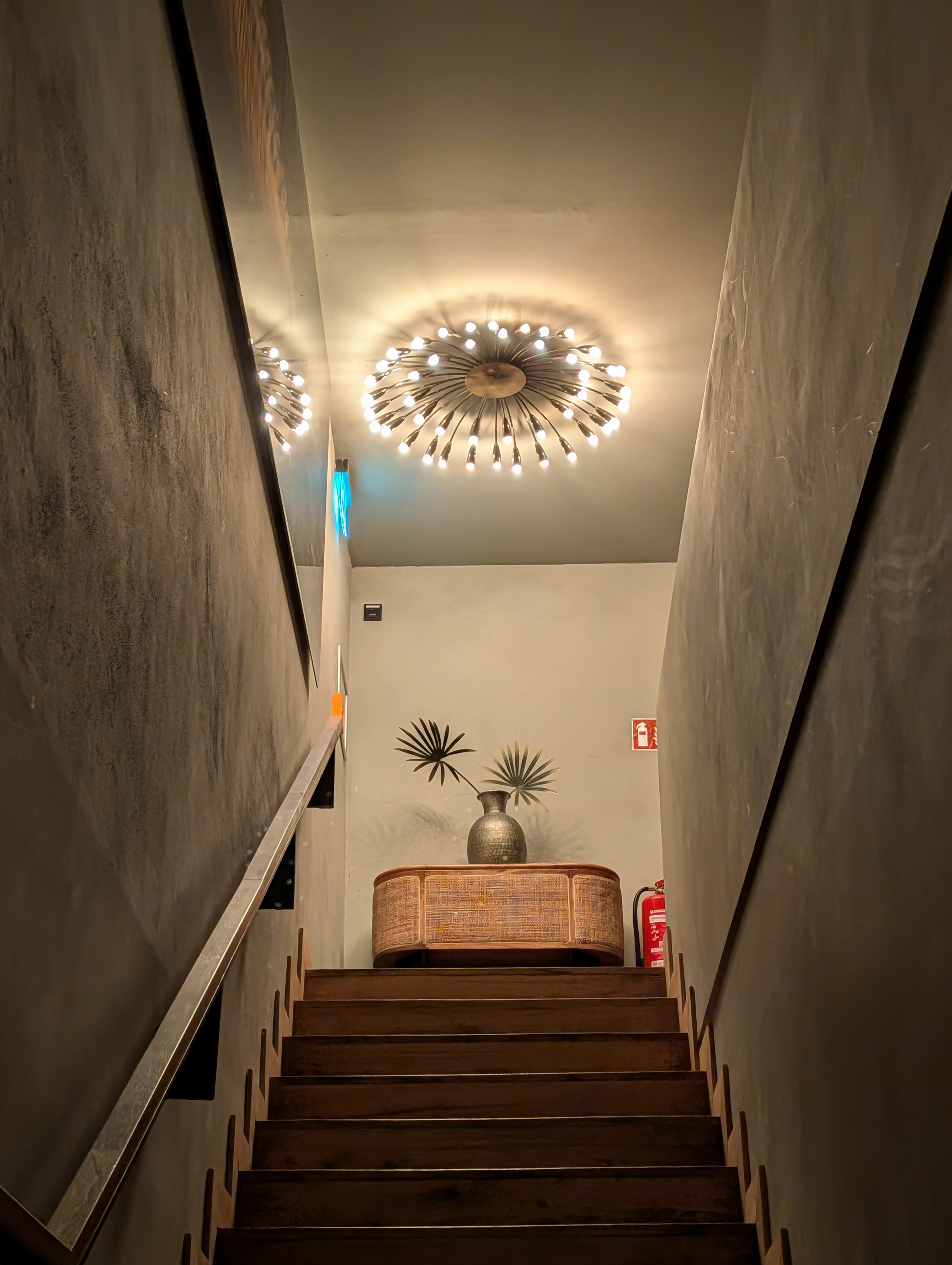 A staircase lit by a chandelier