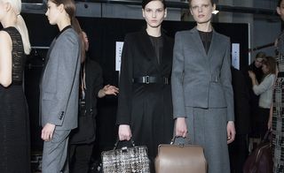 2 female models in suits, carrying briefcase bags