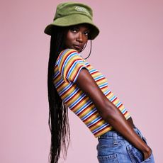 a model wears a green bucket hat and a striped T-shirt