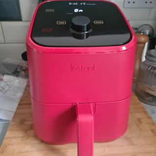 Pink Instant Vortex Mini Air Fryer on wooden cutting board in kitchen
