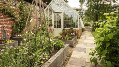 upcycling ideas showing raised beds with reclaimed sleepers in front of a greenhouse