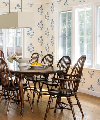 dining room with dark wood table and windsor style chairs with blue floral wallcovering