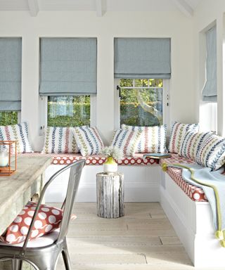 White conservatory with patterned cushions and roman blinds