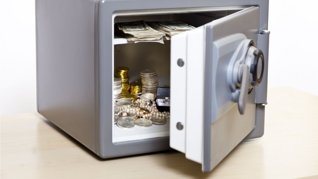 Jewels and cash are visible through the open door of a small safe.