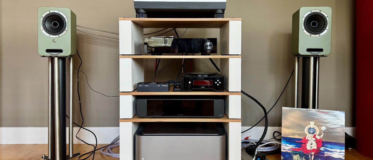 Fyne Audio Cubitt 5 stereo speaker system, as part of a wider hi-fi setup, on a wooden surface.