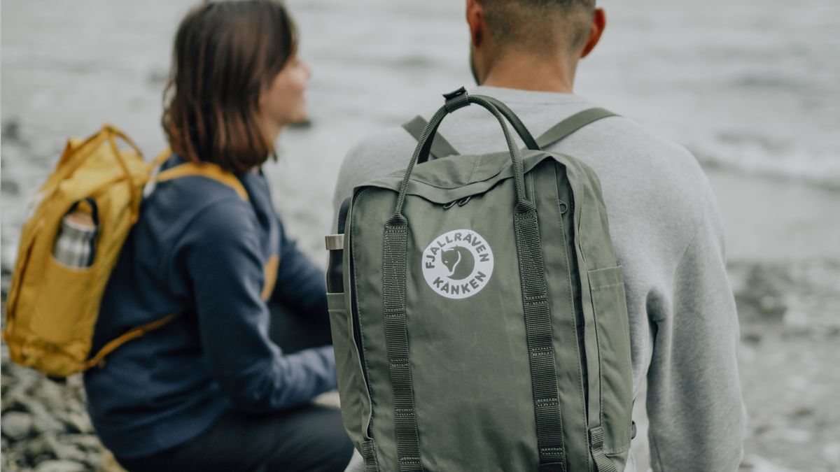 A couple on a beach wearing Fjallraven backpacks