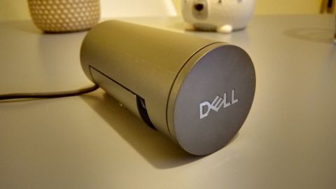 A black Dell Pro Webcam sitting on a grey table and mounted on a laptop.