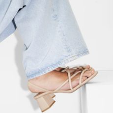Close up of blue jeans and beige heeled sandals 
