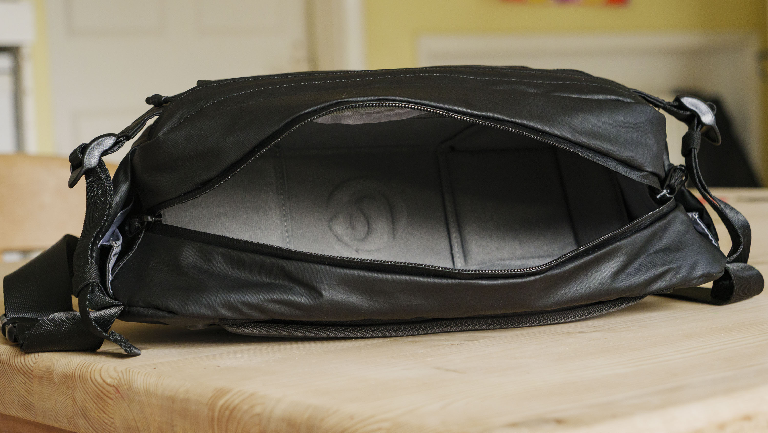 The Ulanzi Camera Sling Bag on a wooden table, main compartment open