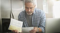 An older man looks worried as he looks over financial paperwork.