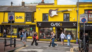 People walk past the yellow-painted Gak Music Emporium and guitar shop in The Lanes conservation area in Brighton, East Sussex, UK