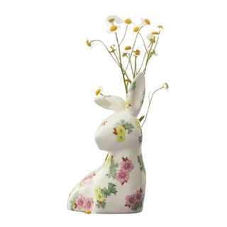 A white ceramic bunny vase with pink and yellow flowers on it, with white and yellow daisy stems coming out of it