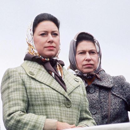 Princess Margaret and Queen Elizabeth wearing tweed coats and head scarves with serious expressions 