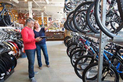 A salesperson is pointing to bikes on two levels to a customer in a bike shop