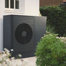 Vaillant aroTHERM plus air source heat pump installed on a home exterior with plants nearby