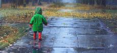 Toddler running in autumn rainy park