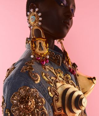 Woman wearing big gold earrings and gold breasts on her jacket