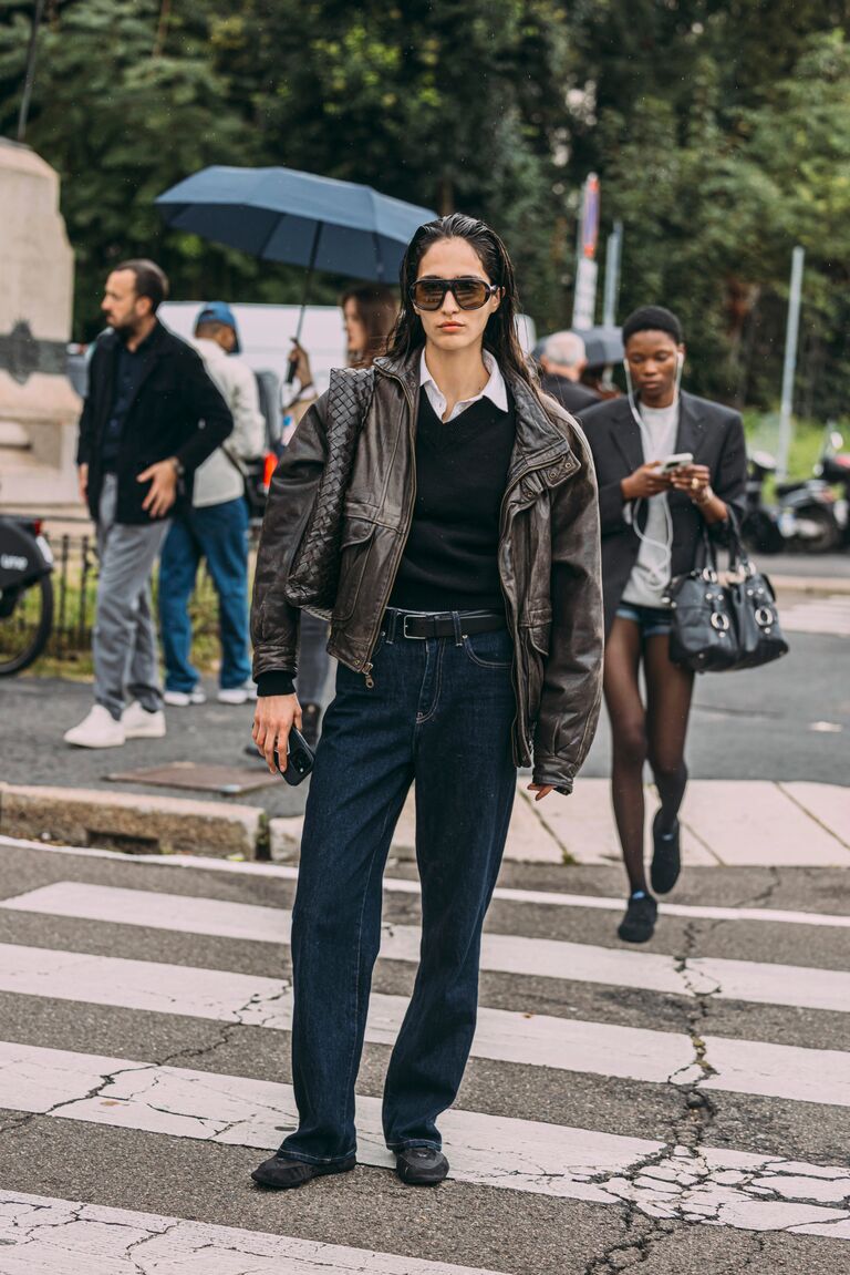 Woman in a V-neck sweater, jeans, and a leather jacket.