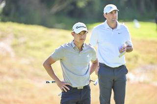 Collin Morikawa and Scottie Scheffler wait to putt on the green