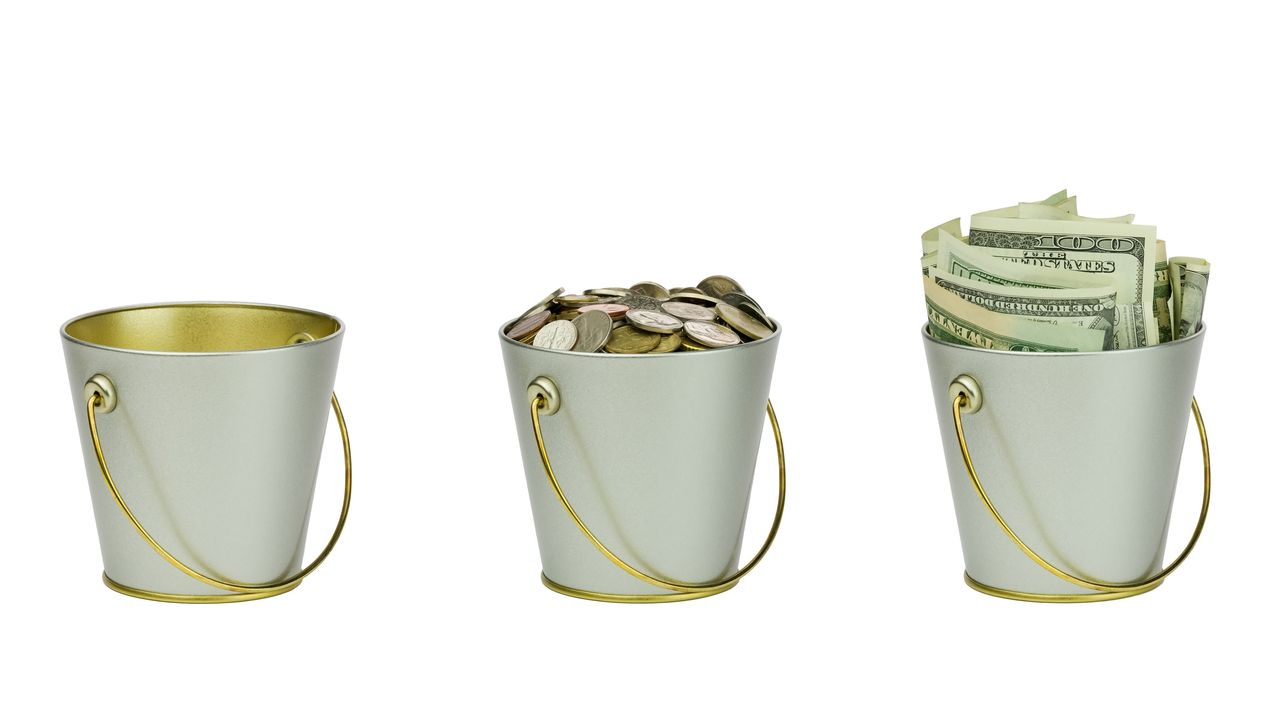 Three buckets are lined up. One looks empty, one has coins in it, and the third is filled with cash.