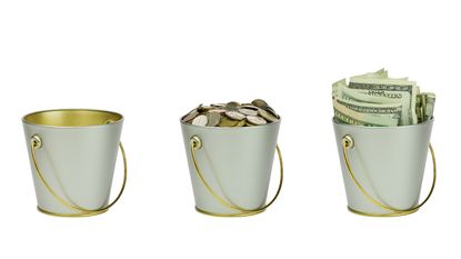 Three buckets are lined up. One looks empty, one has coins in it, and the third is filled with cash.