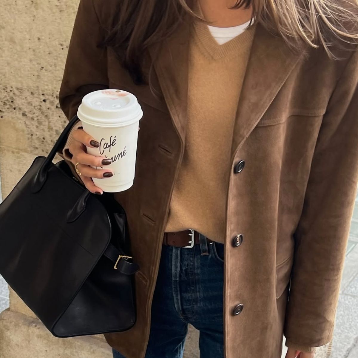 Felicia Akerstrom wearing a suede jacket and holding a coffee