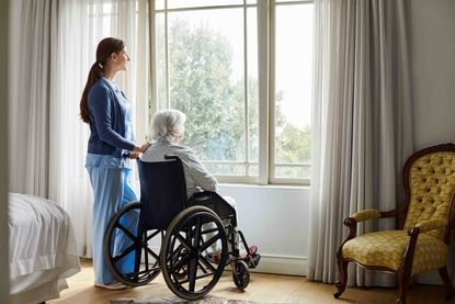 Older woman in wheelchair with nurse looking out a window
