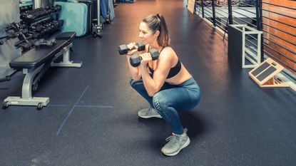 Woman performing a front squat with dumbbells