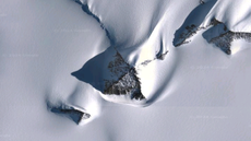 Aerial view of a pyramid-shaped peak in the Ellsworth Mountains of Antarctica. The peak is visible among a deep field of snow.