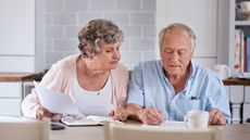 A senior couple sit in their kitchen looking over their HSA contributions.