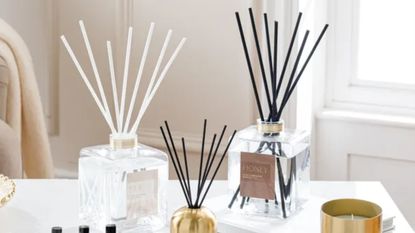 Two large reed diffusers next to a small reed diffusers on top of a kitchen counter